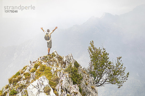 Italien  Massa  Mann jubelt auf einem Gipfel in den Alpi Apuane