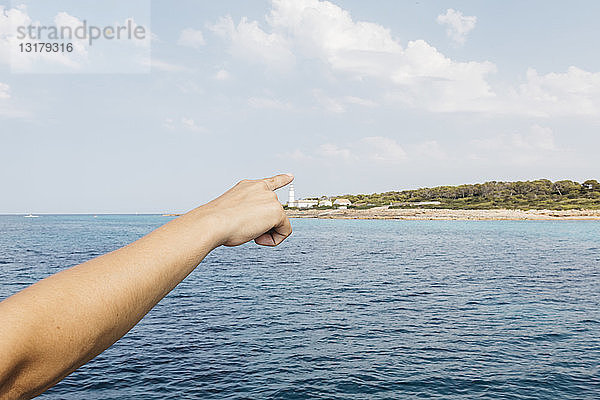 Hand einer Frau  die auf den Leuchtturm von Cap Balnc zeigt  Mallorca  Spin