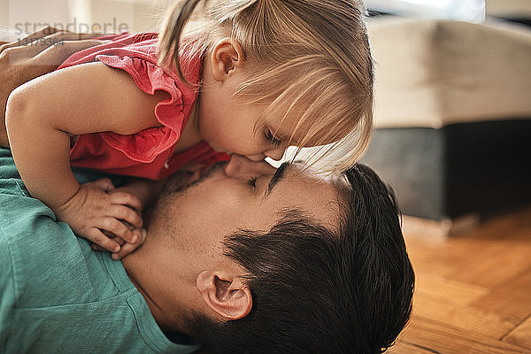 Vater und kleine Tochter kuscheln zu Hause zusammen