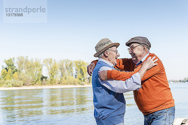 Zwei alte Freunde treffen sich am Flussufer und umarmen sich freudig
