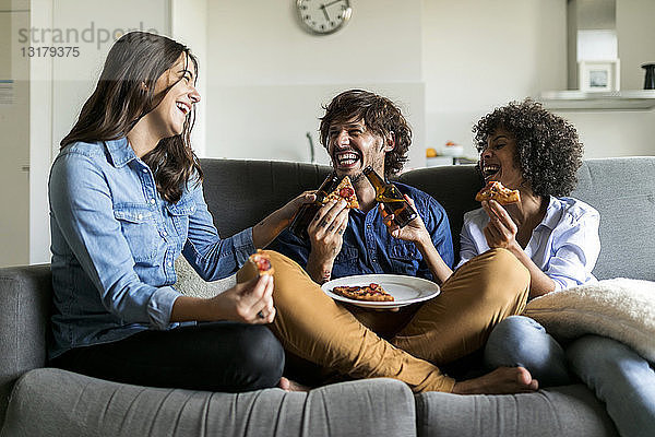 Fröhliche Freunde sitzen auf der Couch  trinken Bier und essen Pizza
