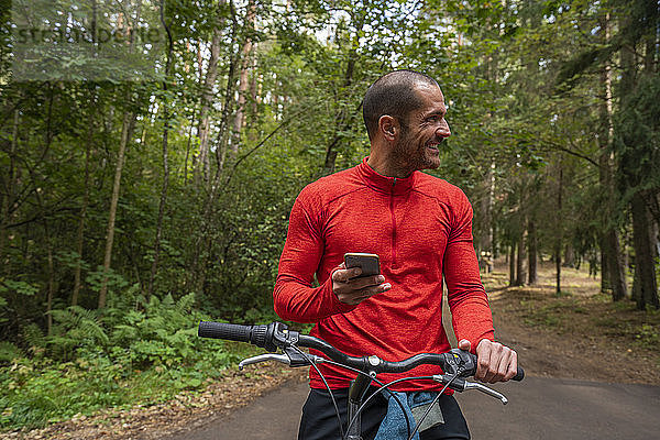 Mountainbiker mit Smartphone in einem Wald