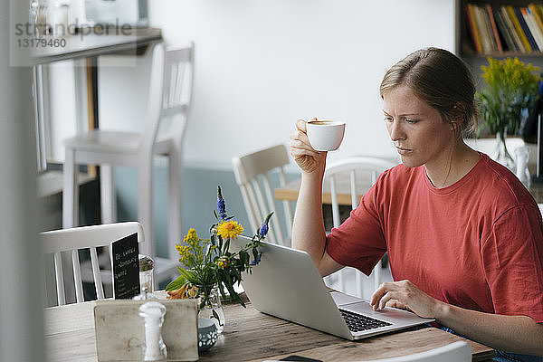 Junge Frau mit Laptop am Tisch in einem Café