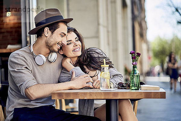 Glückliches  anhängliches junges Paar im Freiluftcafé