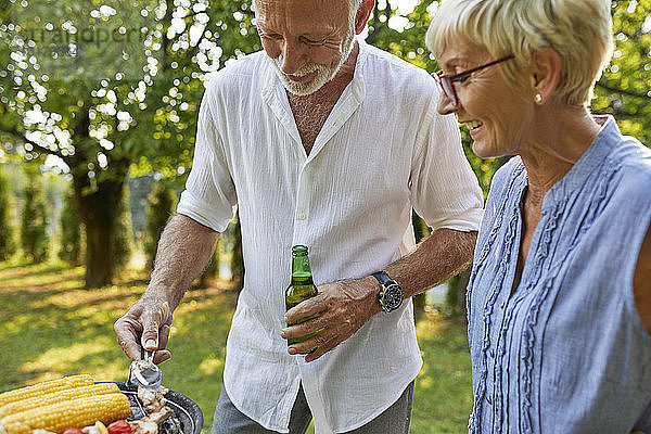 Älteres Ehepaar beim Grillen im Garten