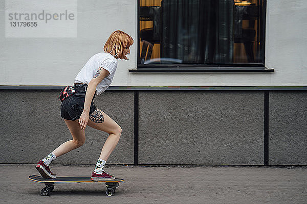Junge Frau fährt Carver-Skateboard auf dem Bürgersteig