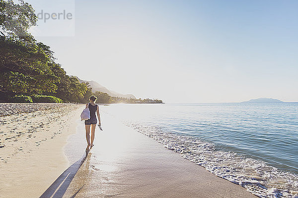 Seychellen  Mahe  Beau Vallon Beach  Frau  die bei Sonnenuntergang am Strand spazieren geht