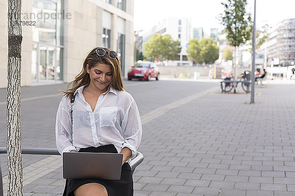 Lächelnde Geschäftsfrau benutzt Laptop im Freien