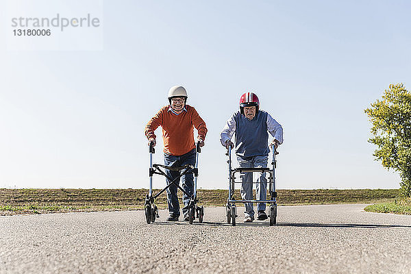 Zwei alte Freunde tragen Schutzhelme und nehmen an einem Laufrad-Rennen teil