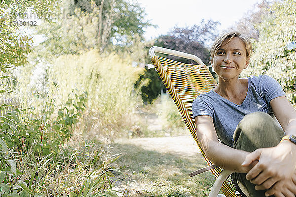 Frau sitzt im Garten auf einem Stuhl