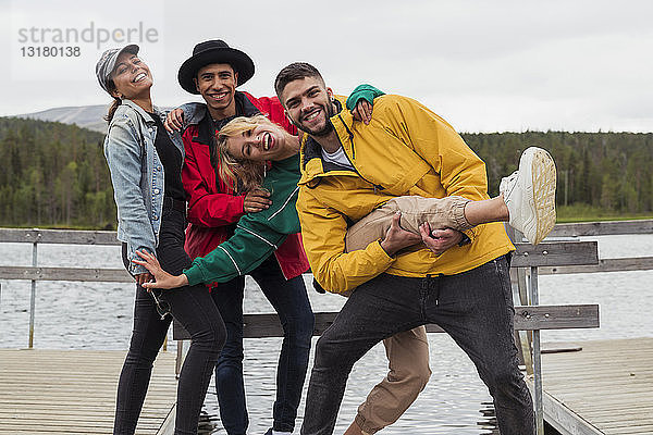 Finnland  Lappland  Porträt fröhlicher  verspielter Freunde auf einem Steg an einem See