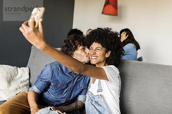 Glückliches Paar  das auf der Couch sitzt und ein Selfie