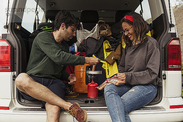 Junges Paar bereitet Würstchen auf einem Campingkocher zu
