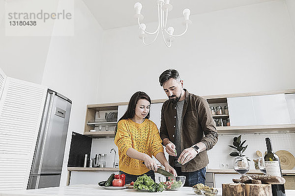 Ehepaar bereitet in moderner Küche gemeinsam Salat zu