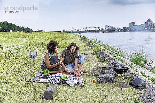 Deutschland  Köln  Ehepaar beim Grillen am Flussufer