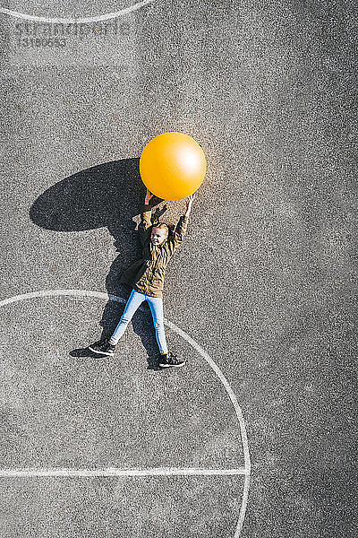 Österreich  Luftaufnahme eines Basketballfeldes  Mädchen mit großem Ball auf dem Boden liegend
