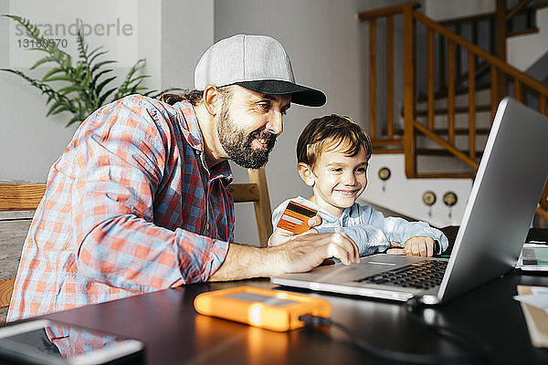 Vater und Sohn benutzen gemeinsam einen Laptop  Online-Shopping