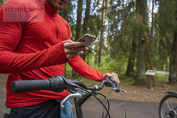 Mountainbiker mit Smartphone in einem Wald