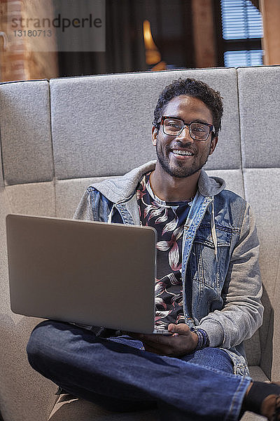 Junger Mann arbeitet in einem kreativen Start-up-Unternehmen und benutzt einen Laptop