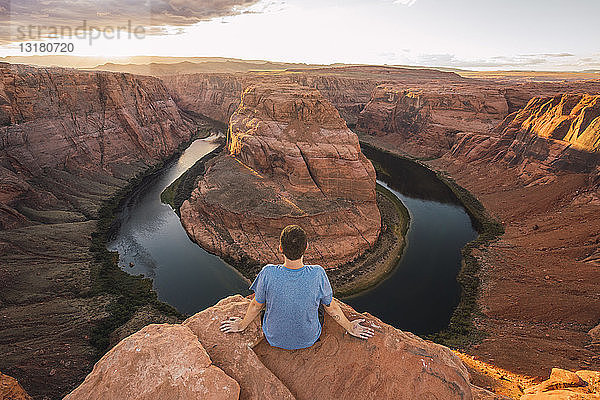 USA  Arizona  Colorado River  Horseshoe Bend  junger Mann auf Aussichtspunkt sitzend
