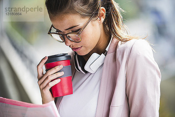 Porträt einer jungen Geschäftsfrau  die Dokumente liest und eine Kaffeetasse hält