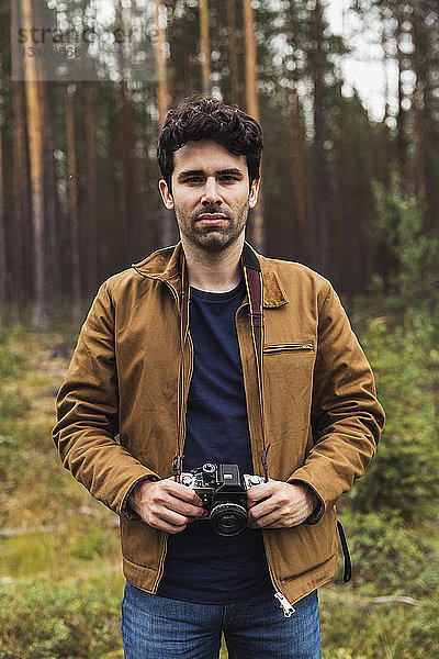 Finnland  Lappland  Porträt eines jungen Mannes mit Kamera in ländlicher Landschaft