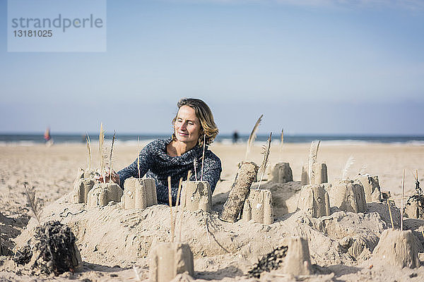 Reife Frau baut eine Sandburg am Strand