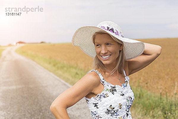 Lächelnde reife Frau auf abgelegenem Feldweg im Sommer