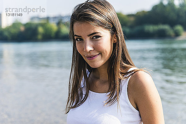 Porträt einer lächelnden jungen Frau am Flussufer