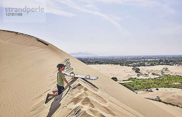 Peru  Ica  Junge mit Sandbrett auf Sanddüne