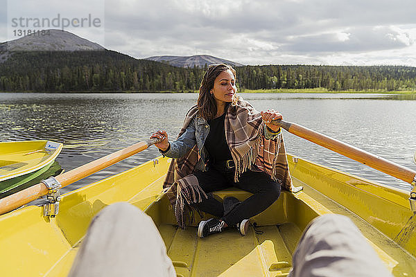 Finnland  Lappland  Frau mit einer Decke in einem Ruderboot auf einem See