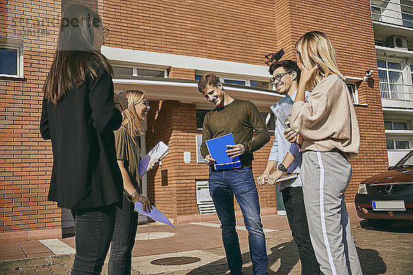 Gruppe glücklicher Studenten  die mit Dokumenten im Freien stehen