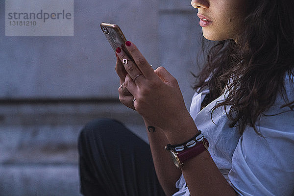 Junge Frau benutzt Handy in der Dämmerung  Teilansicht