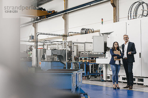 Geschäftsmann und Frau in einem High-Tech-Unternehmen  die sich in einer Fabrikhalle treffen