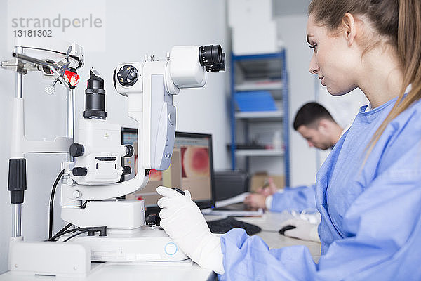 Labortechniker  der im Labor mit dem Mikroskop arbeitet