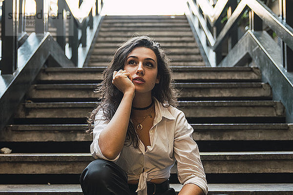 Porträt einer jungen Frau  die auf einer Treppe sitzt