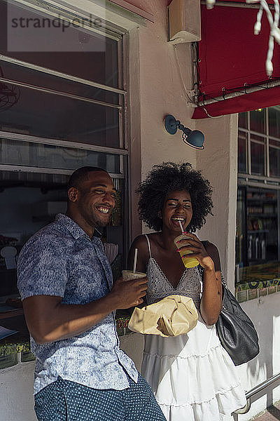 Glückliches junges Paar bei einem Drink am Kiosk