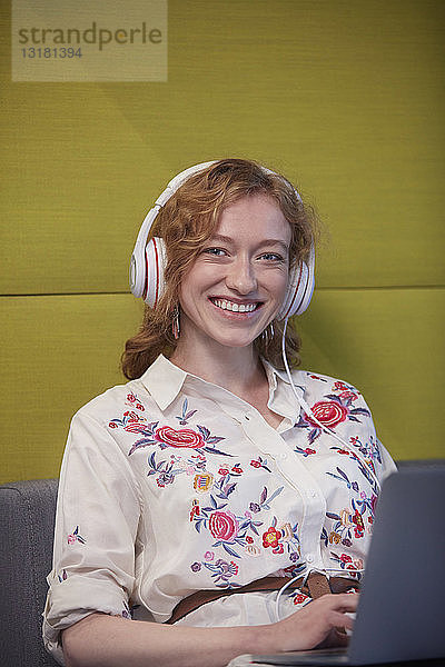 Junge Frau  die in einem modernen Kreativbüro arbeitet und Kopfhörer trägt