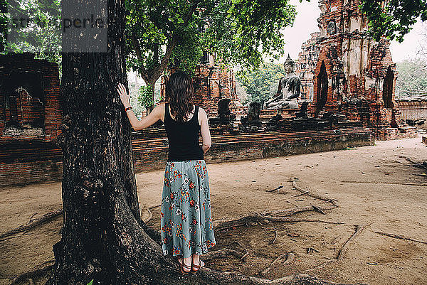 Thailand  Ayutthaya  Frau betrachtet eine Buddhastatue im Wat Mahathat