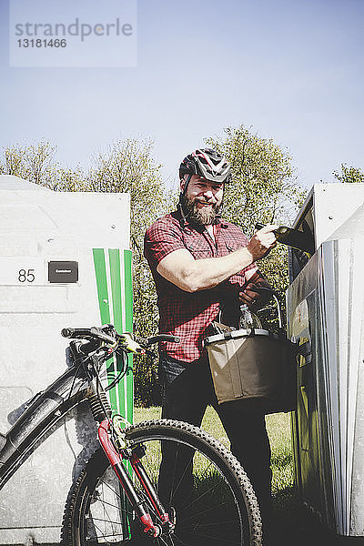 Porträt eines Mannes  der Glasflaschen in Flaschen recycelt Radfahrer