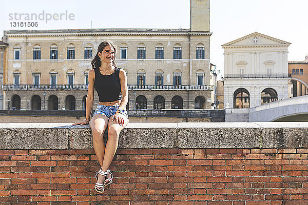 Italien  Pisa  junge Frau sitzt auf einer Mauer in der Stadt