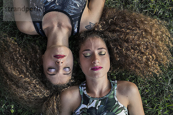 Porträt der Zwillingsschwestern in Rouge auf einer Wiese liegend  Draufsicht