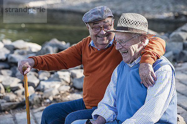Zwei alte Freunde sitzen am Flussufer und amüsieren sich