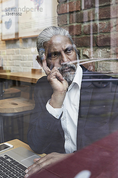 Porträt eines nachdenklichen Senior-Geschäftsmannes in einem Café  der aus dem Fenster schaut