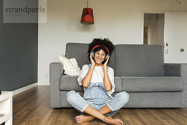 Glückliche Frau sitzt zu Hause mit Kopfhörern