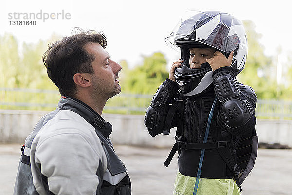 Vater beobachtet Sohn beim Aufsetzen des Motorradhelms