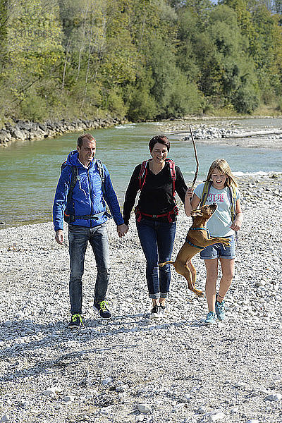 Familienwanderung mit Rucksäcken und Hund an der Isar  Oberbayern  Deutschland