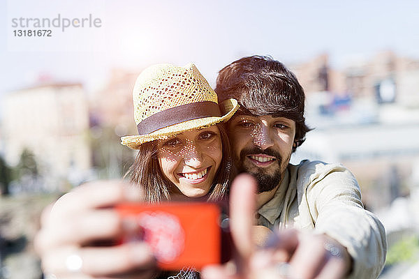 Porträt eines glücklichen jungen Paares  das sich mit einem Smartphone selbstständig macht