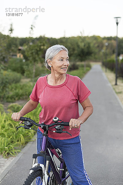 Ältere Frau mit Fahrrad auf dem Fahrradweg