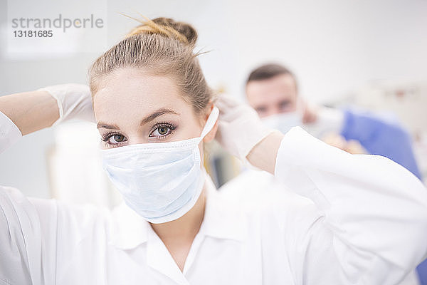 Porträt eines Laboranten beim Anlegen der Maske